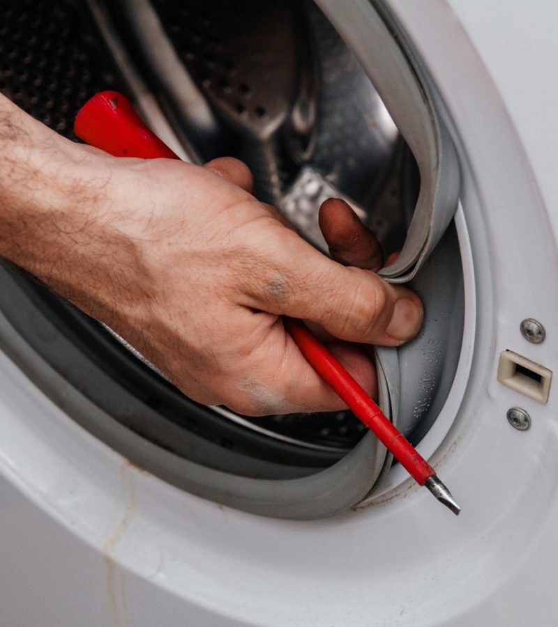 Handyman repairing a washing machine. The hands of a man repair a washing machine. Close-up